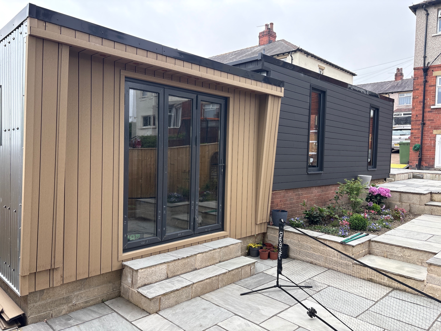L-shaped office and studio with cedar-effect contrast wall, raised entrance and integrated planter steps.